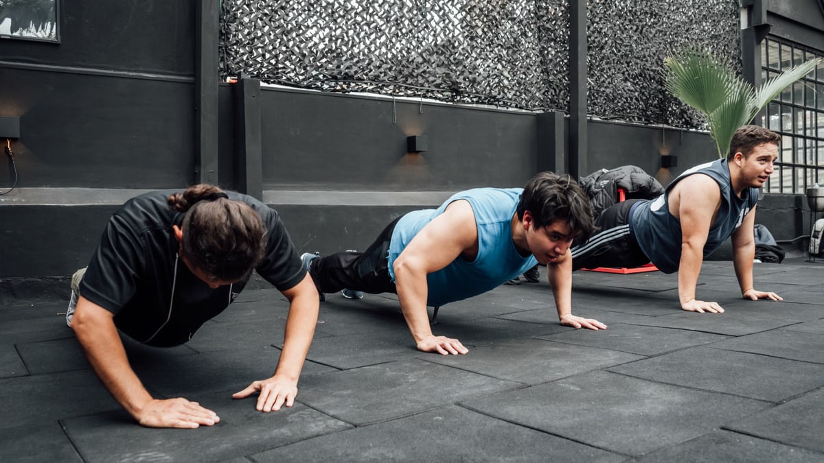 Men performing push-ups during a group workout session in Mexico City gym.